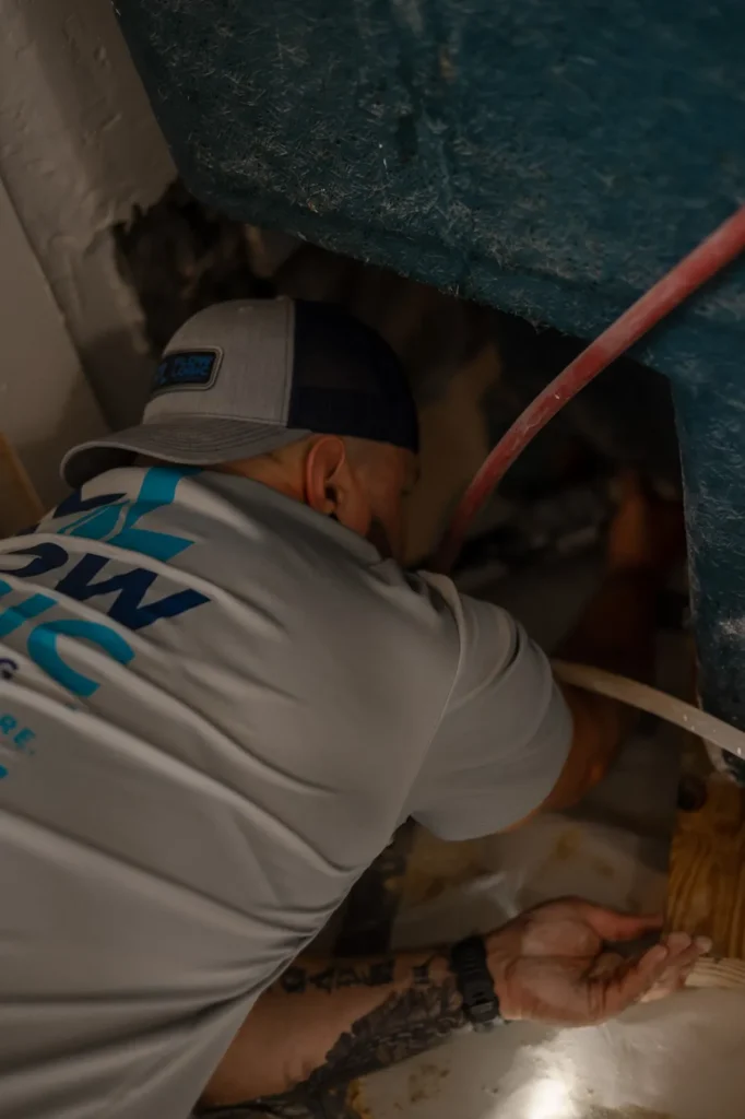 Flow Logic technician repairing plumbing under a sink